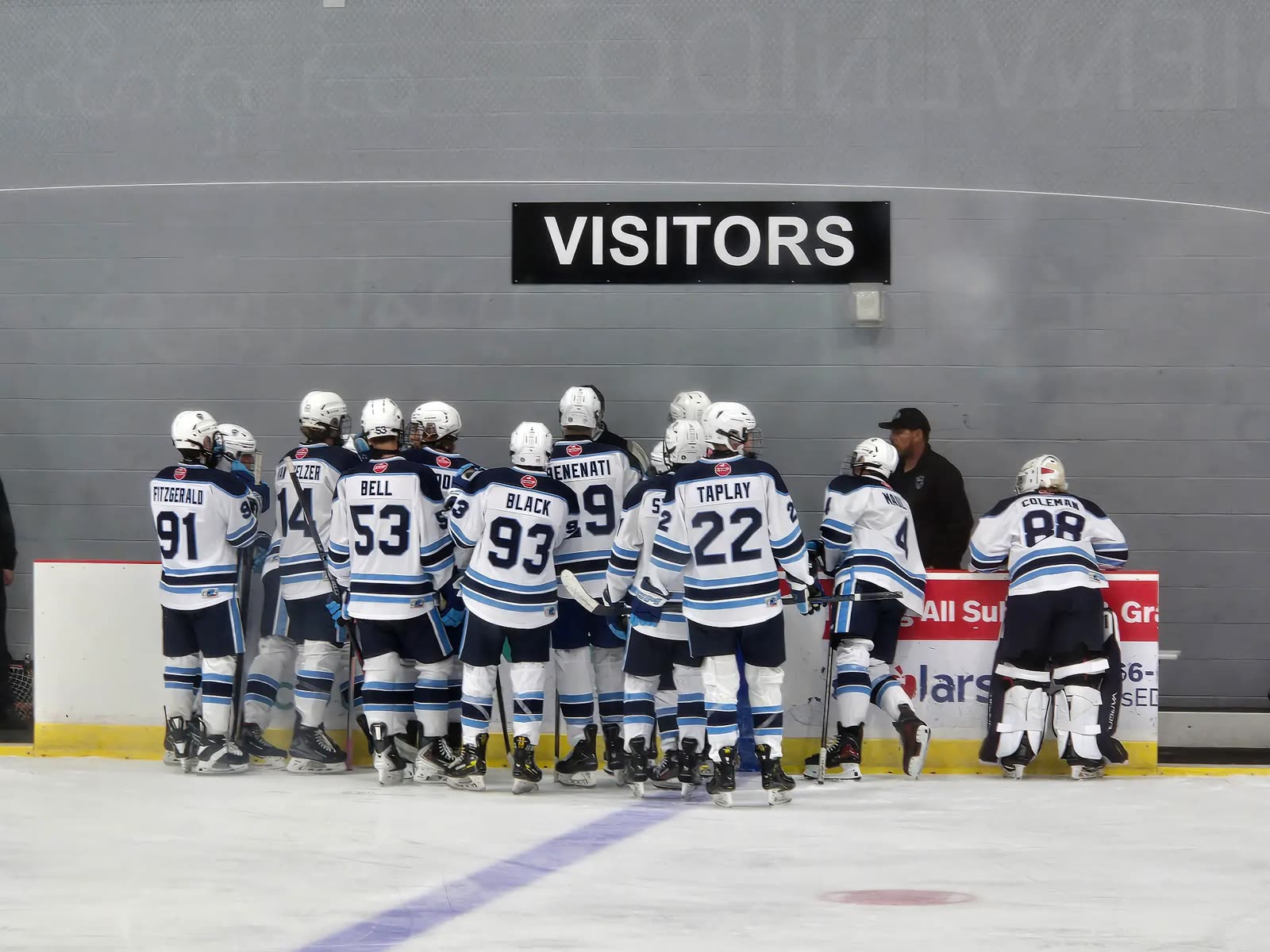 Jr. Mustangs Hockey players gathered beneath the visitors sign