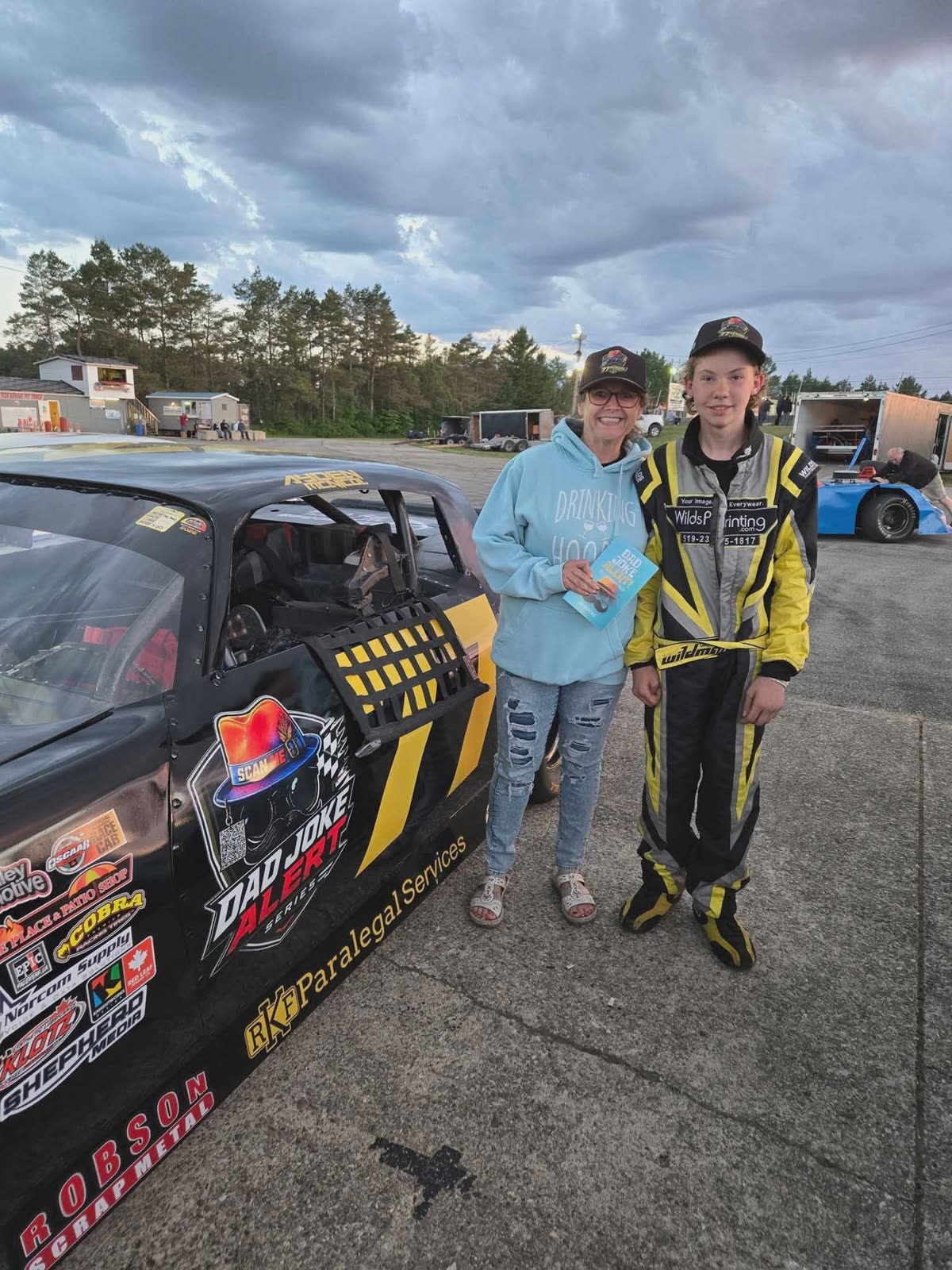 Tina in a blue hoodie with Ayden beside the #77 Hot Rod